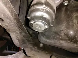 Filtre à huile de voiture sous le véhicule, avec une clé carrée insérée.