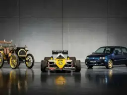 Trzy samochody Renault: zabytkowy, bolid F1 i współczesny, na tle szarej ściany.
