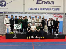 Młodzi sportowcy świętują sukces na mistrzostwa polski juniorów. Drużyna z transparentem "Czarni do boju" pozuje na podium.