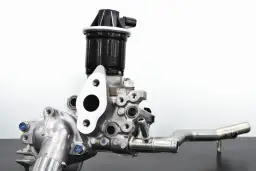 Metalowy element układu recyrkulacji spalin (EGR). Widoczny zawór z czarną obudową i metalową podstawą, połączony z rurą.