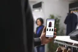 Mężczyzna przegląda trendy ecommerce na telefonie, wybierając koszulę w sklepie.