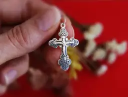 Srebrny krzyż prawosławny w dłoni. Różnice między prawosławiem a katolicyzmem mogą być widoczne w symbolice.