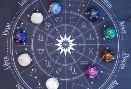 Kości do gry z symbolami zodiaku i cyframi, w tym kostka z numerologiczną 10, leżą na tle wykresu astrologicznego.