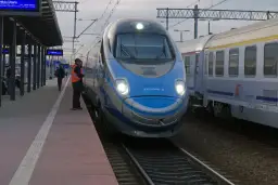 Pendolino Warszawa-Kraków na peronie. Maszynista w kamizelce odblaskowej czeka na pasażerów.