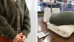 Primer plano de un cárdigan verde tejido y ovillos de hilo, mostrando diferentes tipos de fibras textiles.