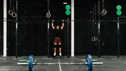 Mężczyzna wykonuje podciąganie na drążku w siłowni CrossFit.
