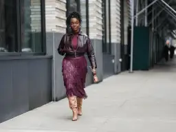 Mujer con falda de flecos burdeos y chaqueta a juego, luciendo botas altas. Un ejemplo de cómo combinar zapatos burdeos mujer con estilo.