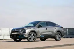 Szary Citroen C4X z niebieskimi akcentami stoi na betonowym placu.