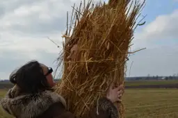 Kobieta w futrzanym płaszczu przytula się do słomianego chochoła, jak wygląda chochoł z wesela.