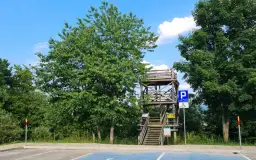 Drewniana wieża widokowa Szczerbanówka z widocznymi schodami i parkingiem.