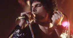 Freddie Mercury śpiewa z pasją, jakby chciał porwać tłumy. Choć nie ma tu dzieci, jego muzyka to dziedzictwo dla przyszłych pokoleń.