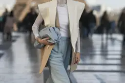 Elegancka stylizacja: jak nosić kamizelkę damską z szerokimi spodniami i błękitną torebką.