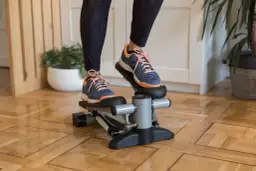 Ćwiczenia na stepperze w domu. Osoba w sportowych butach wykonuje trening, który angażuje mięśnie nóg i pośladków.