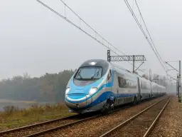 Pendolino pędzi po torach, łącząc Kraków z Warszawą. Pociąg PKP Intercity wjeżdża w mglisty krajobraz.