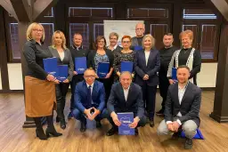 Grupa osób pozuje do zdjęcia z niebieskimi folderami. Na folderach widnieje napis "Platforma Obywatelska".