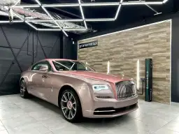 Luksusowy Rolls-Royce w różowym odcieniu, prezentujący efektowne oklejenia samochodu.