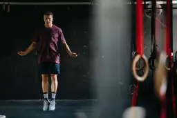 Mężczyzna w sportowym stroju skacze na skakance w siłowni.