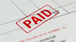 Czerwony stempel "PAID" na dokumencie, który może być fakturą zaliczkową a VAT.