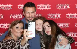 Katarzyna Skrzynecka z rodziną robi selfie. Uśmiechnięci rodzice i ich dzieci pozują na tle czerwonego banera z napisem "Teatr Capitol".