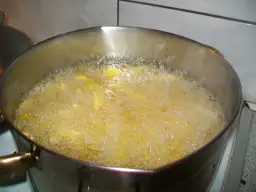 Frytki smażące się w głębokim oleju w metalowym garnku.