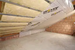Izolacja poddasza z wełny mineralnej Isover Vario KM Duplex UV. Montaż na stelażu, widoczna folia paroizolacyjna i ściana z cegły.