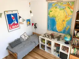 Pokój dziecka po metamorfozie: łóżko w paski, dinozaury i mapa Afryki.