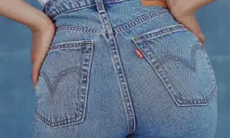 Zbliżenie na tył dżinsowych spodni z widocznymi kieszeniami i czerwoną metką Levi's.