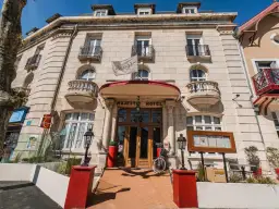 Façade de l'hôtel Majestic à Châtelaillon-Plage avec son entrée principale en bois et un drapeau blanc.