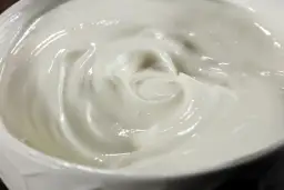 Textura cremosa y suave de alioli con leche, con remolinos que invitan a probarlo.