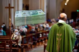 Ksiądz w zielonej szacie podczas mszy, obok krzyża stos banknotów. Ile kosztuje msza w intencji zmarłego?