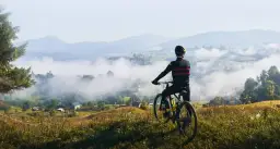 Rowerzysta podziwia mglisty krajobraz Dolnego Śląska. Widok na dolinę i góry.