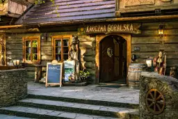 Drewniana karczma góralska, przyciągająca licznymi atrakcjami. Przed wejściem drewniane rzeźby, beczki i kamienne murki.