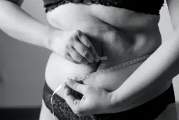 Kobieta mierzy talię centymetrem, szukając sposobu, jak schudnąć 5 kg w 3 dni.