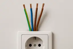 Cztery przewody wychodzące z gniazdka elektrycznego: zielono-żółty, niebieski i dwa brązowe. Jaki kabel do instalacji elektrycznej w domu?