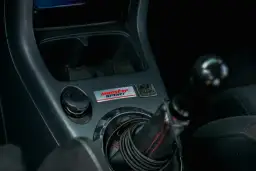 Wnętrze samochodu z naklejką "Monster Sport" i gniazdem zapalniczki. Który bezpiecznik jest od zapalniczki?