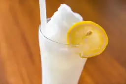 Un refrescante granizado de limón, coronado con una rodaja de limón fresco, listo para disfrutar en un día caluroso.
