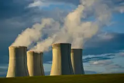 Chłodnie kominowe elektrowni jądrowej na tle burzowego nieba. Czy energia jądrowa jest ekologiczna? Dym unoszący się z kominów budzi pytania.