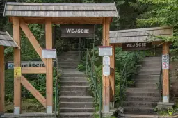 Kamienne schody prowadzą do wejścia na Szczeliniec Wielki. Drewniane zadaszenia i tablice informacyjne zapraszają do zwiedzania.
