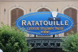 Panneau bleu lumineux de Ratatouille, l'aventure totalement toquée de Rémy, devant un bâtiment.