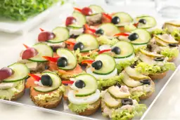Kolorowe kanapki na talerzu, idealne na pan kanapka catering. Różne dodatki: łosoś, jajko, ogórek, oliwki, winogrona.