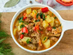 Aksamitna zupa gulaszowa przepis prosty, pełna mięsa, ziemniaków i papryki, posypana natką pietruszki.