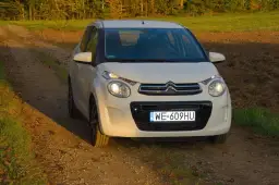 Biały Citroen C1 na tle jesiennego krajobrazu, na drodze gruntowej.
