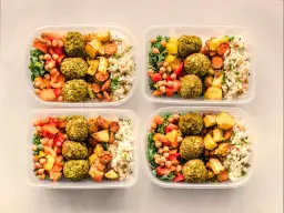 Cztery pojemniki z posiłkami: falafel, ryż, pieczone warzywa i sałatka. Idealny jadłospis na dietę dobrych produktów.