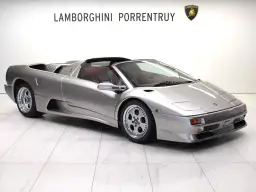 Srebrny kabriolet Lamborghini Diablo z czerwonym wnętrzem, zaparkowany na białej, marmurowej podłodze.