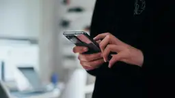 Dłonie trzymające nowoczesny smartfon, widok z bliska.