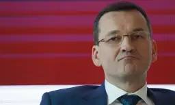Mateusz Morawiecki w garniturze i okularach na tle czerwono-fioletowych pasów.