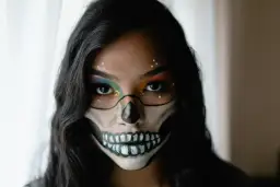 Makijaż na Halloween w stylu sugar skull: czarne kontury czaszki, kolorowe cienie do powiek i błyszczące dżety.