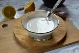 Kremowe aioli w miseczce, obok cytryna i czosnek. Idealne do dipów i sosów.