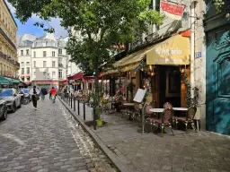 Ulica w dzielnicy łacińskiej Paryża z kawiarnią "La Petite Boulangerie" i brukowanym chodnikiem.