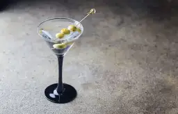 Elegancki dirty martini z trzema oliwkami na wykałaczce, gotowy do degustacji.